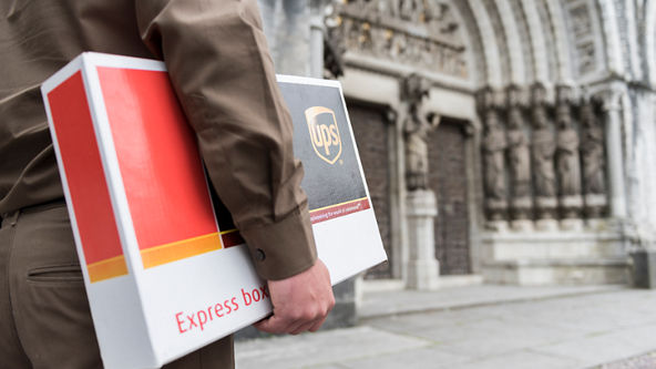 UPS delivery driver holding UPS express box on street