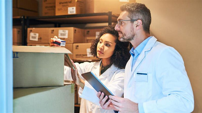 Tablet, box and pharmacy with people and inventory for shipping, cargo or medical supplies. Digital, checklist and delivery with man and woman in storage room for medicine, healthcare and drugs store; Shutterstock ID 2304125633; purchase_order: Channel Partners; job: ; client: ; other: 