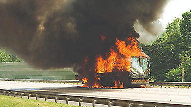 Semi truck on fire on the side of the highway. 