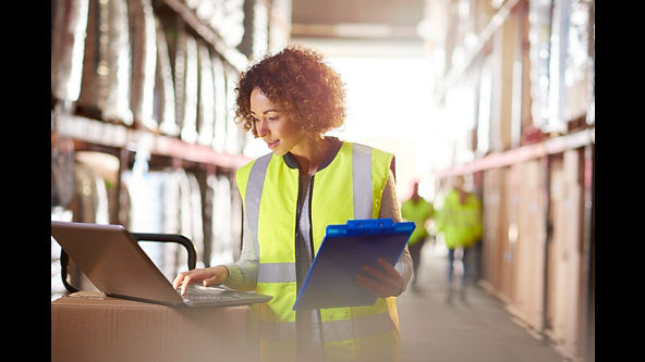 Women in logistics looking at a computer with a clipboard