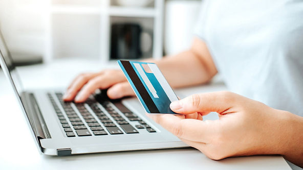 Close up of a hand using a laptop while the other holds a credit card 