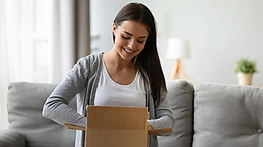 Female sitting on a couch with her hands in an open box