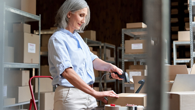 Female scanning a box in a store room full of boxes