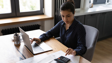 Woman looking at computer and using calculator