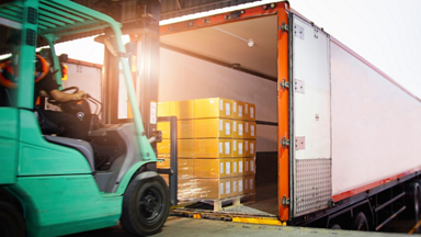 Fork lift putting a pallet of boxes into the back of a semi-truck 