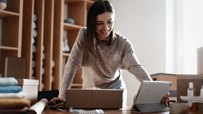 Female with a packaged box using a tablet 