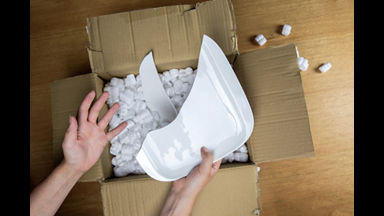 Broken plate in damaged cardboard box top view, damaged home delivery unpacking box close up