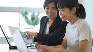 Two females working on laptops together 