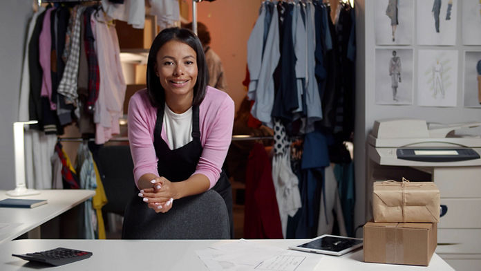 Female leaning on the back of a chair at a clothing business