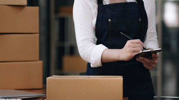Female writing on a clipboard next to boxes 