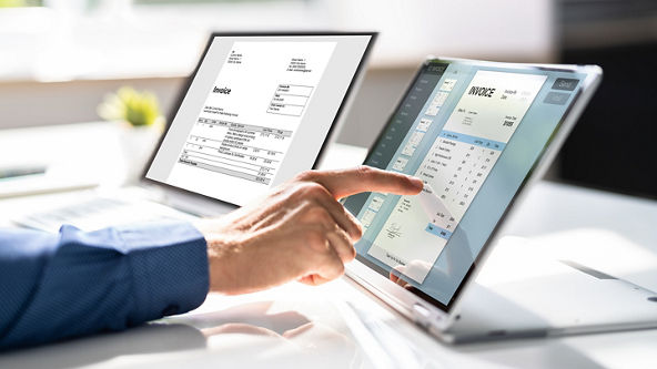 Close up of a hand using a tablet on the table next to a laptop 