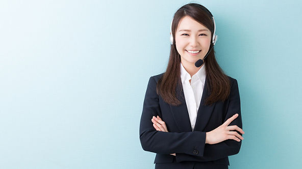 Female wearing a headset and folded arms in front of a blue background