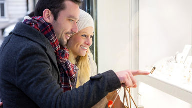 Male and female looking in a jewelry store display window