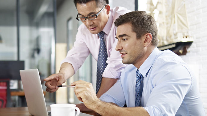 Two males looking and pointing at a laptop 