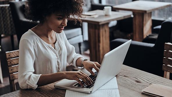 Female typing on her laptop at a café table 