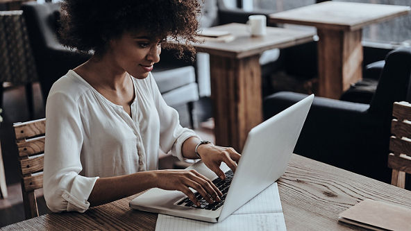 Female typing on her laptop at a café table 